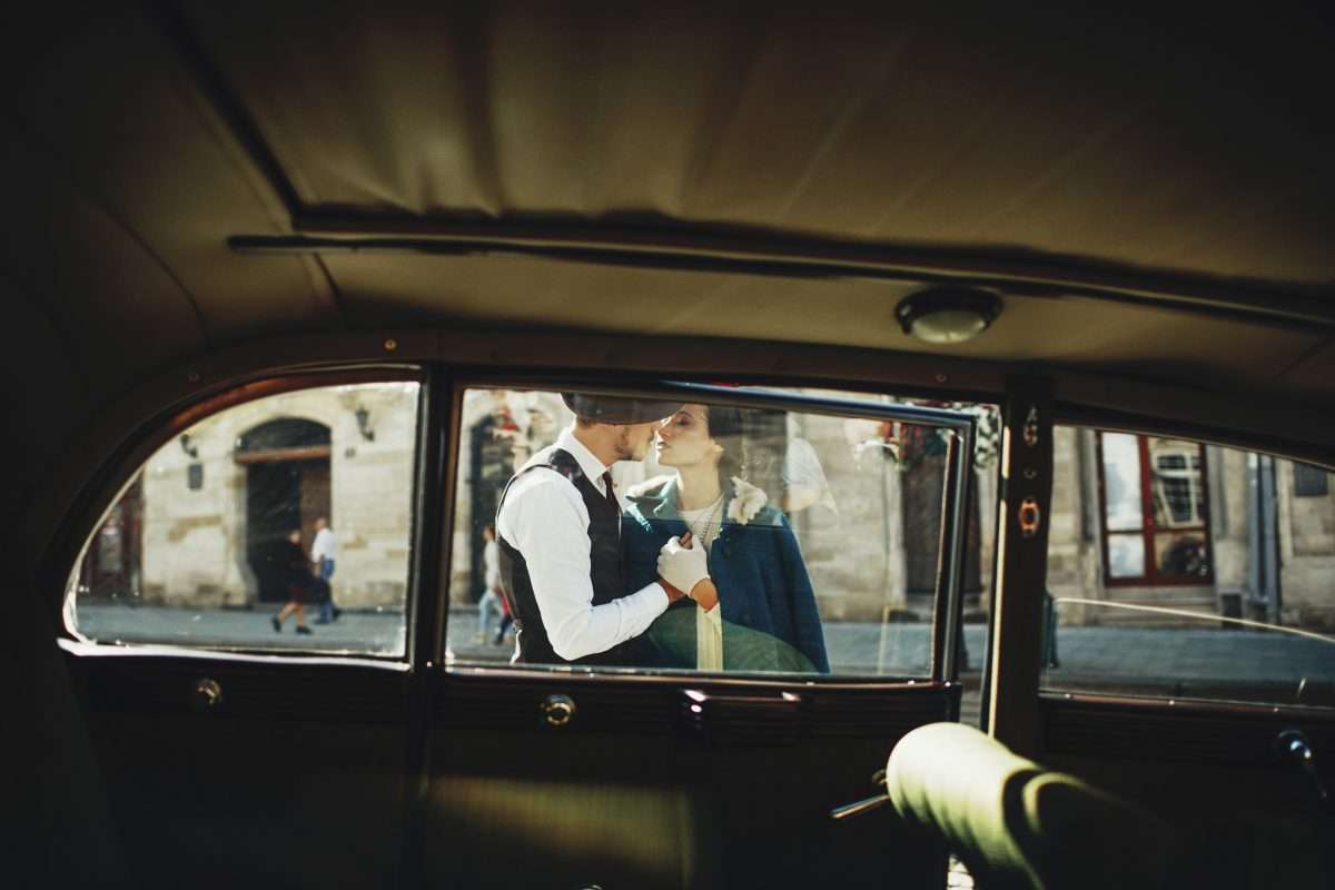 Look through the retro car at a man and woman dressed in old fas
