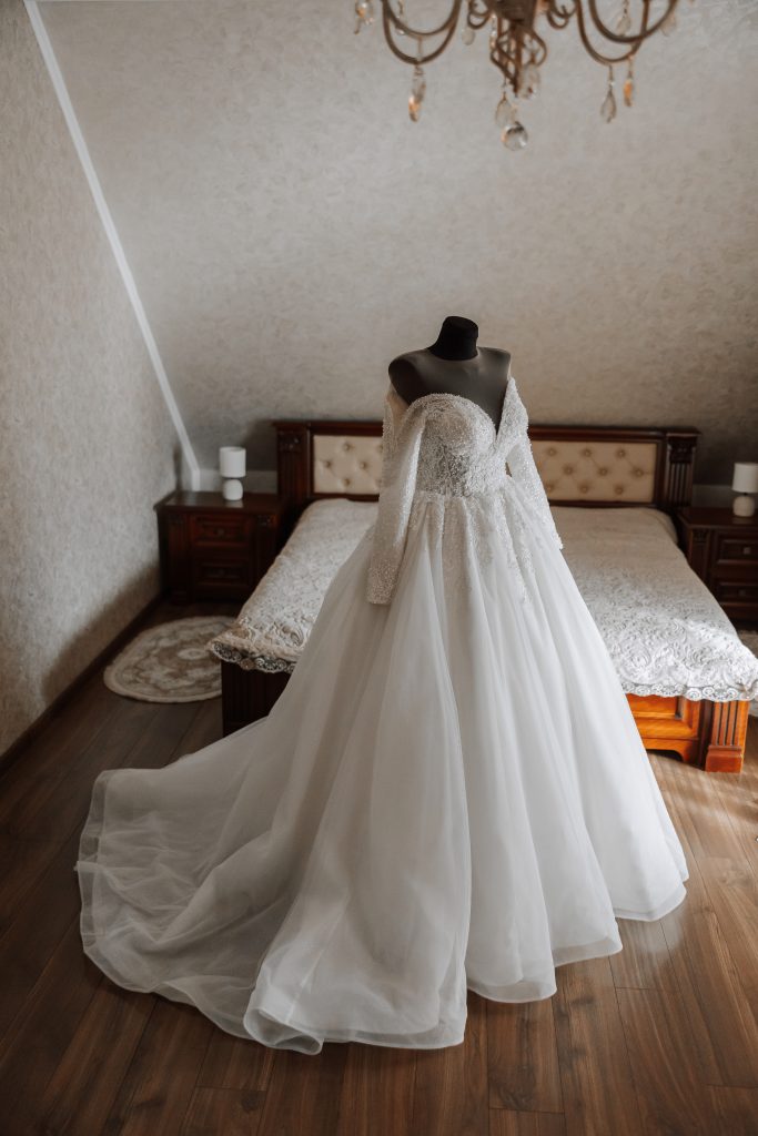 Bedroom interior with wedding dress prepared for the ceremony. A beautiful lush wedding dress on a mannequin in a hotel room.